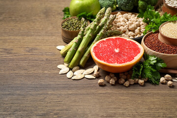 Fresh vegetables, grapefruit and seeds on wooden table, space for text