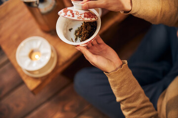 Young man holding bowl with dried tea leaves