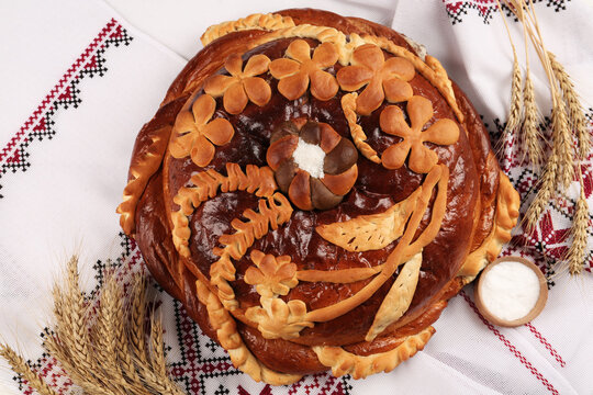 Korovai with wheat spikes on rushnyk, flat lay. Ukrainian bread and salt welcoming tradition