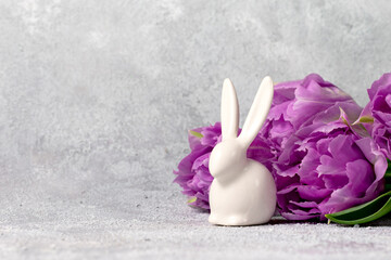 Festive composition with purple tulips and ceramic white rabbit. Easter design. Copy space