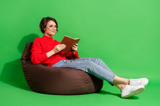 Full size profile photo of optimistic nice brunette hairdo lady lie on bag read wear red sweater isolated on green color background