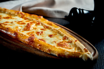 Turkish pide dish with tomatoes and salted cheese on black background