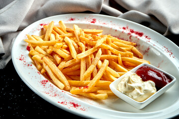 Appetizing side dish - French fries with mayonnaise and ketchup in a white plate