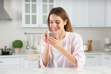 Young woman drinking chocolate milk in kitchen