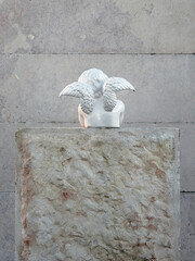 small white angel statue facing the wall