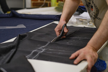 Dressmaker cutting dress fabric on sketch line. Fashion designer tailor or sewer in workshop studio designing new collection clothes. Business owner shop and entrepreneur concept