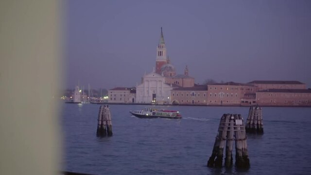 Night handheld view of Venice Church capella from window as river boat passes