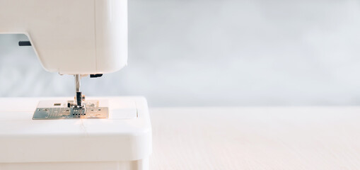 Modern sewing machine for repairing or sewing clothes on a desktop light background selective focus
