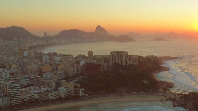 Aerial appraoching Copacabana Beach and Sugarloaf Mountain from Arpoador at sunrise