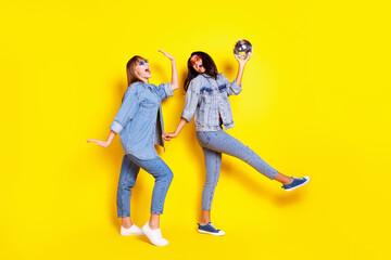 Fototapeta na wymiar Full body portrait of two carefree excited buddies dark skin hold disco ball isolated on yellow color background
