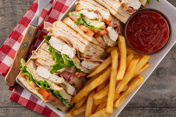 Club sandwich and French fries with ketchup sauce on wooden table	