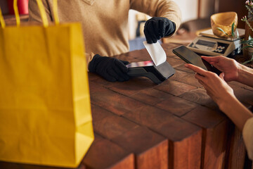 Male worker in gloves using terminal for contactless payment