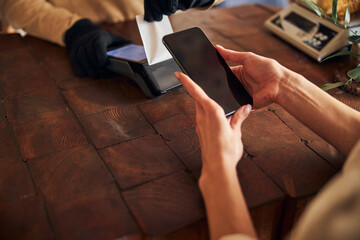 Young woman using smartphone to pay for purchases
