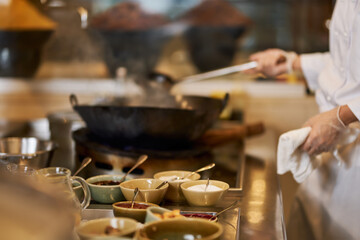 Fragment photo of chef putting more ingredients into wok