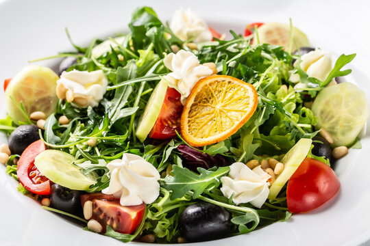 Greek salad with arugula, cream cheese, pine nuts, tomato, black olives and cucumber. healthy vegan lunch bowl. Food recipe background. Close up