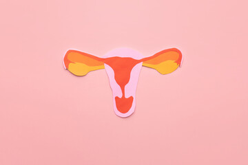 Uterus shape made frome paper on pink background. Awareness of uterus illness such as endometriosis, PCOS, STDs or gynecologic cancer. Female reproductive health concept.