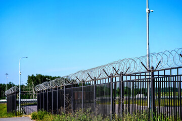 The restricted area is fenced with a fence with barbed wire. A fence around a restricted area with CCTV cameras on poles