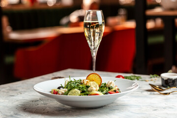 Greek salad of fresh cucumber, tomato, arugula, cream cheese, pine nuts and olives with olive oil. Restaurant menu, dieting, cookbook recipe