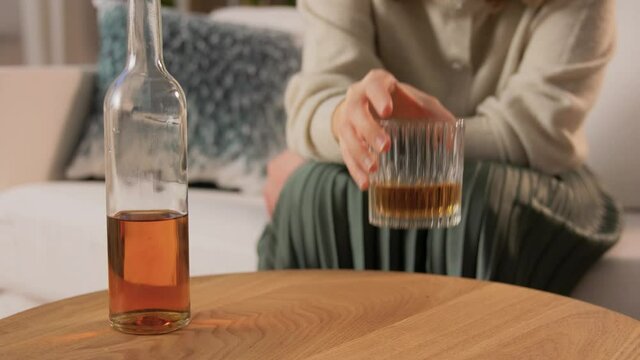 alcoholism, alcohol addiction and people concept - drunk woman or female alcoholic drinking whiskey at home