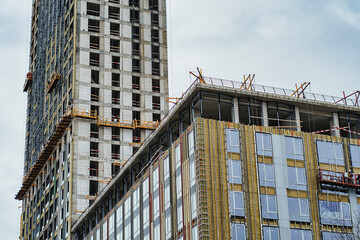 Residential high-rise building under construction. Unfinished house on a construction site with cranes.