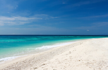 Fototapeta na wymiar sandy beach with turquoise sea water and bright blue sky