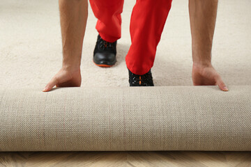 Worker rolling out new carpet flooring indoors, closeup
