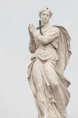 Fototapeta na wymiar Ancient statue of beautiful praying Saint Angel with sword in her chest at the top of Arsenal in Venice, Italy, details, closeup.