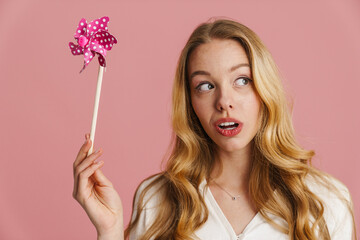 Cheerful young blonde woman playing with windmill toy
