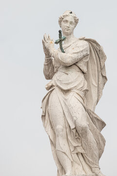 Ancient statue of beautiful praying Saint Angel with sword in her chest at the top of Arsenal in Venice, Italy, details, closeup.