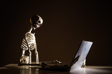 Artificial human skeleton sitting at a laptop, Concept of exhaustion at work