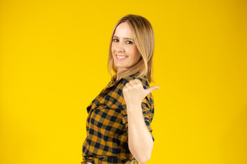 Young woman over isolated yellow background pointing finger to the side