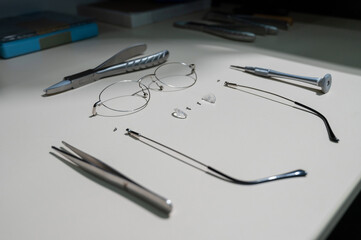 Disassembled glasses frame and tools. Optics work table.