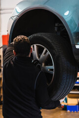 Mechanic changing car wheel in auto repair shop.