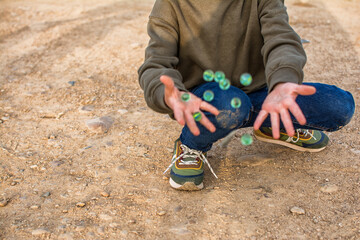 Marbles.
Child Playing Marbles On The Ground.