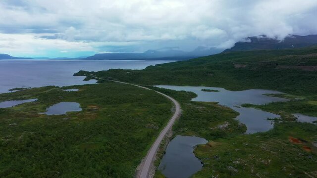 Aerial view of a arctic road, lake and the Lapporten mountains, dark, moody day, in North Sweden - tilt, drone shot