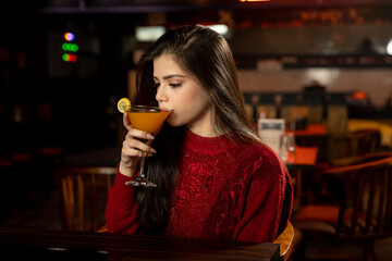 Portrait of a pretty female drinking juice while sitting in a restaurant.