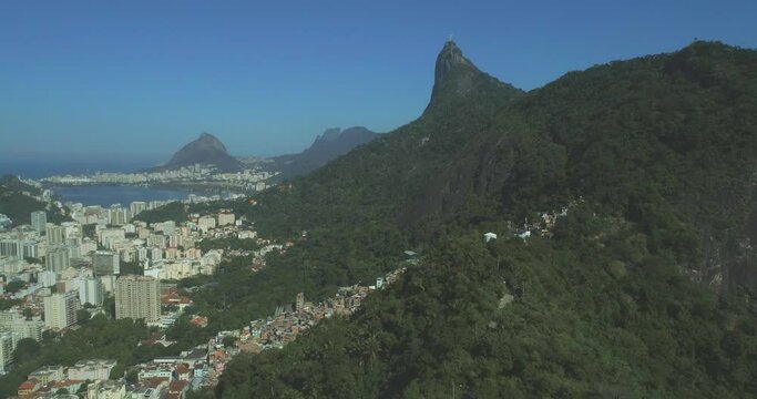 Rio de Janeiro aerial moving over mountains and forest towards Christ the Redeemer in the background with city and favelas below