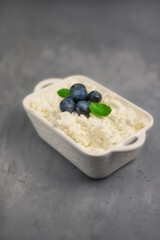 Fresh cottage cheese with blueberries on a concrete background