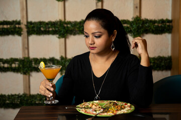 Portrait of a woman holding a glass of juice in a restaurant.