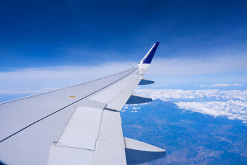 Fototapeta na wymiar Photo of airplane wing with clouds background, horizon line and clear blue sky