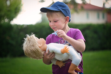 little boy playing with a doll in nature