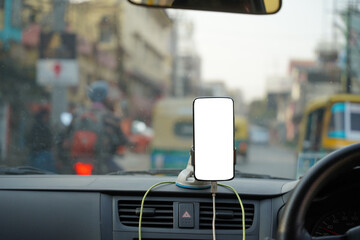 a smartphone held on a dashboard of a cab taxi with mockup white screen for navigation
