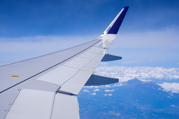 Fototapeta na wymiar Photo of airplane wing with clouds background, horizon line and clear blue sky