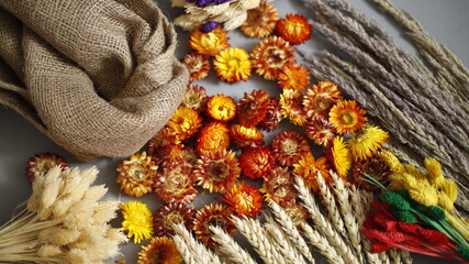 Kwiaty i trawy suche  z tkaniną jutową na szarym tle © Seance_Photo_Sylwia