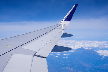 Obraz premium Photo of airplane wing with clouds background, horizon line and clear blue sky
