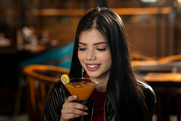 Portrait of a beautiful young Indian girl drinking juice while sitting in a restaurant.