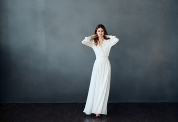 Fototapeta premium Charming lady in a white dress on a gray background dance gesticulating with her hands model