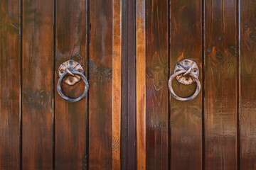 Wooden door with wrought iron handles. Sash of old doors. Wooden gate up close