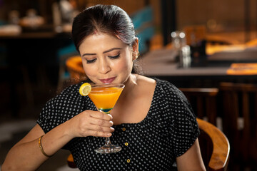 Portrait of a pretty female drinking juice while sitting in a restaurant.
