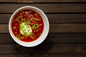 Russian national soup Red Borsch in a plate with sour cream and herbs